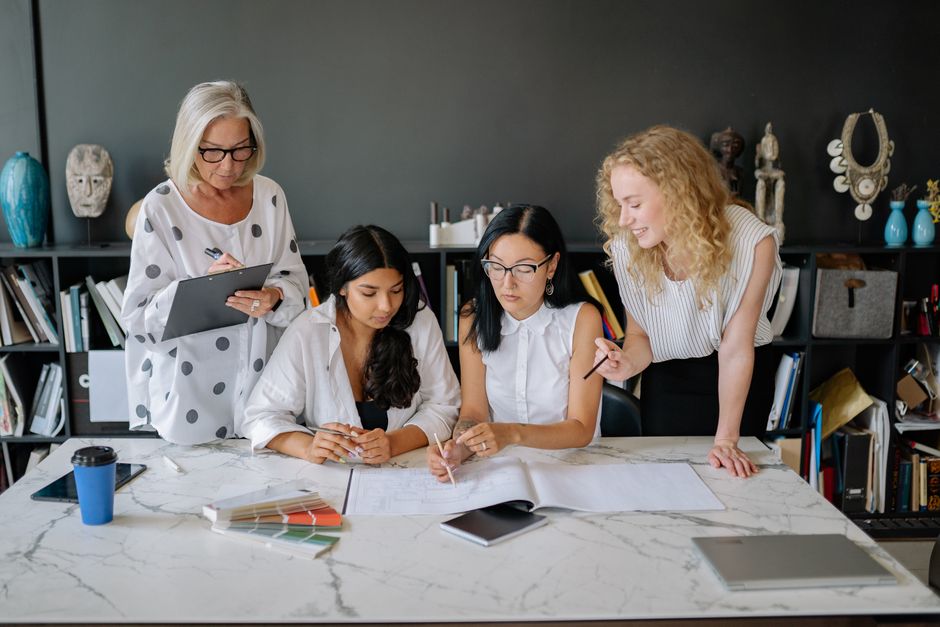 A group of women engaged in collaborative work at a modern office desk.